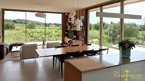 Una cocina moderna con ventanas amplias, una zona de comedor y una estantería.