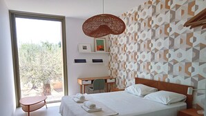 Un dormitorio moderno con una cama grande, un escritorio y una silla. Hay una ventana con vistas a árboles.