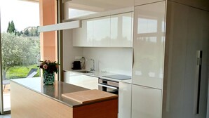 Una cocina moderna con una isla central, armarios blancos y vistas a zonas verdes.