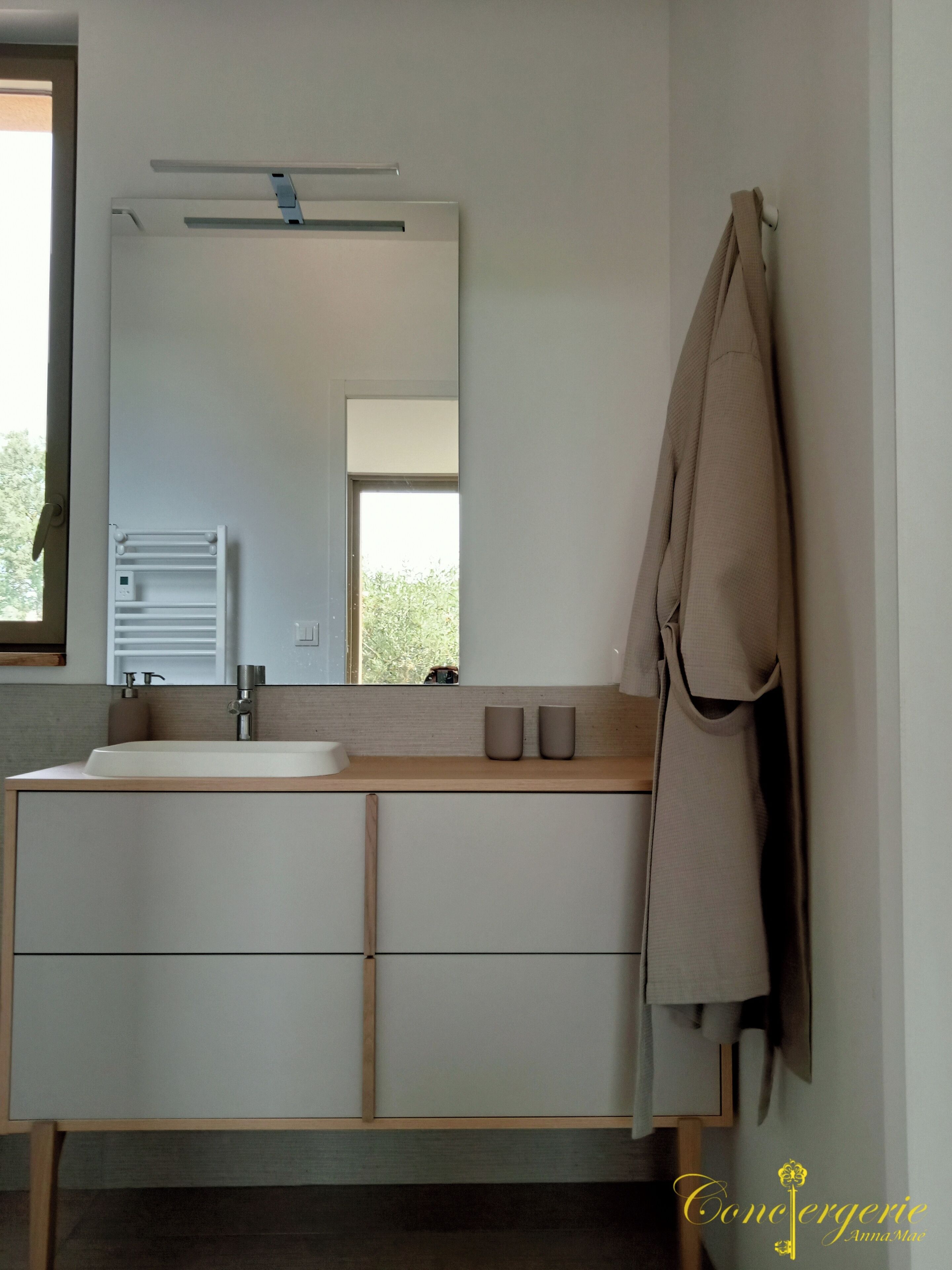 Een moderne badkamer met een grote spiegel, een wastafel en een handdoekhouder.