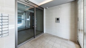 A modern elevator with glass doors, a metal handrail, and a control panel on the wall. - HILLS SAPPORO 203 (Sapporo)