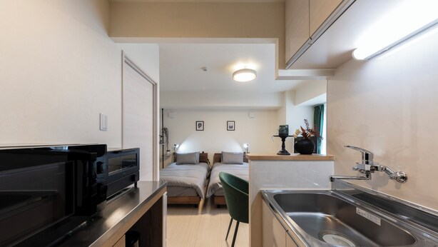 A compact kitchen with a built-in oven, a sink, and a small dining area with a chair. - HILLS SAPPORO 203 (Sapporo)