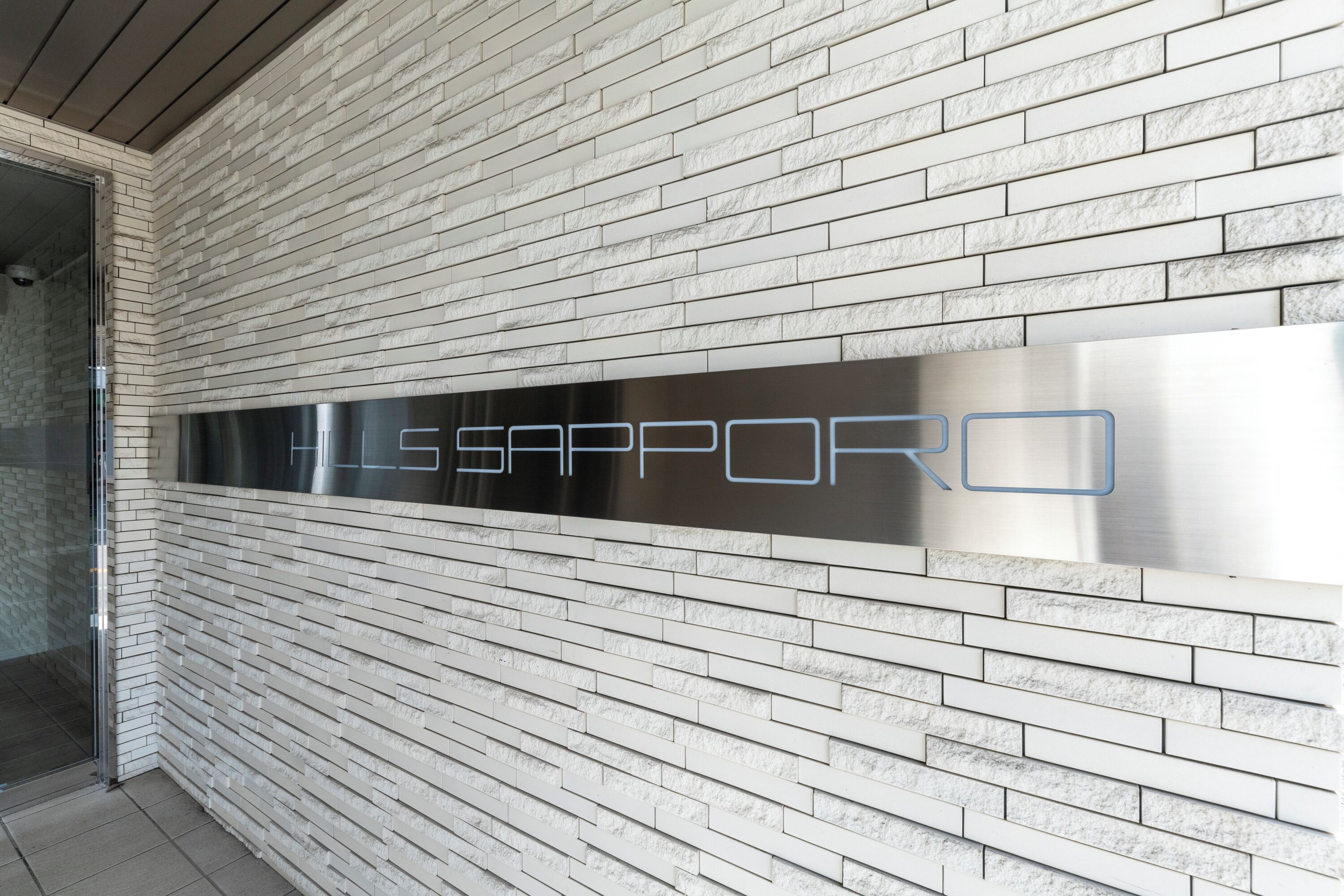 A wall with a metallic plaque reading "LE SAPPORO".
