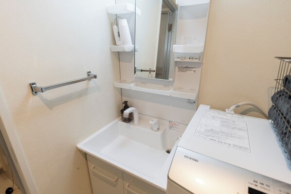 A small bathroom with a white sink, a mirror, a towel rack, and a paper towel dispenser.