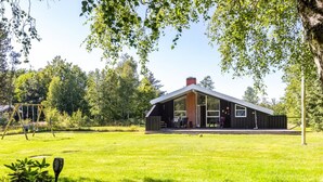 A modern house with a large open porch, surrounded by a well-maintained lawn and trees. - "Olli" - 600m from the sea by Interhome (Jerup)