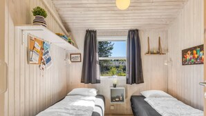 A room with two beds, wooden walls, a window with curtains, a shelf with items, and a hanging light fixture. - "Olli" - 600m from the sea by Interhome (Jerup)
