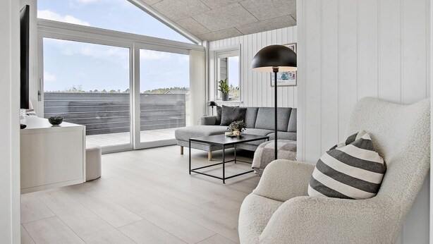 Ein modernes Wohnzimmer mit einem großen Schiebeglastür, die auf einen Balkon führt, einer Couch, einem Couchtisch und einer Stehlampe.