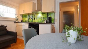 Eine kompakte Küche mit hellen Holzschränken, einem modernen Herd und einer grünen Spritzschutzwand.