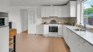 Una cocina moderna con armarios blancos, horno empotrado y un amplio ventanal con vistas al exterior.