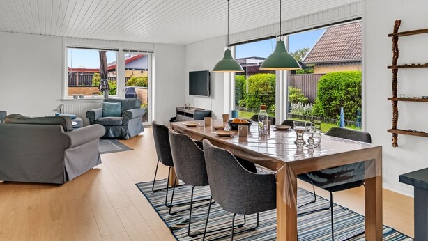 Una sala de estar moderna con comedor, ventanas amplias y vista al jardín trasero.