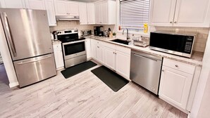 A modern kitchen with white cabinets, stainless steel appliances, and a black countertop. - Bungalow | Upper Level | CT Train | Spruce Meadow (Calgary)