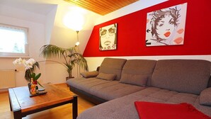 Ein Wohnzimmer mit einer Couch, einem Couchtisch und einer roten Wand mit Kunstwerken.