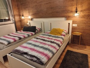 A twin room with two beds, a small round table, and a window with blinds.