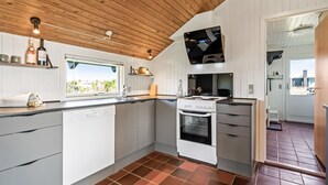 Een moderne keuken met witte kasten, een inbouwoven en een raam met uitzicht op een tuin.