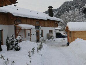 A wooden lodge with a covered entrance, a sign indicating it is a MyWorld property, and a car parked in the snow.