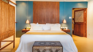 A bedroom with a large bed, wooden headboard, bedside tables, and a small decorative box. - Mua Tala Hotel (El Nido)