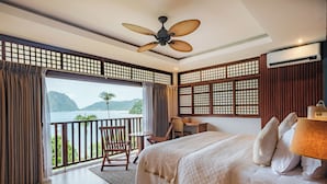 A bedroom with a bed, a desk, a chair, and a view of the mountains. - Mua Tala Hotel (El Nido)