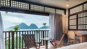 A balcony with wooden chairs, a small round table, and a view of mountains and water. - Mua Tala Hotel (El Nido)