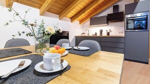 Une cuisine moderne avec un plafond en bois, un four encastré et un coin repas avec une table mise pour deux personnes.