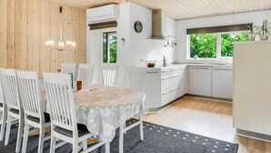 Een moderne keuken met witte kasten, een inbouwoven en een raam met uitzicht op groen.