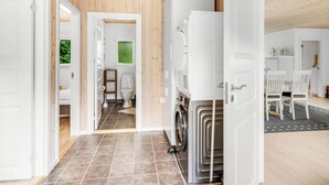Een modern interieur met een zichtbare wasruimte, een kleine badkamer met toilet en raam, en een eetgedeelte met stoelen.