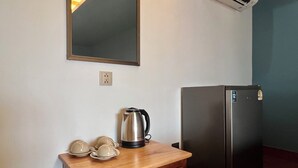 A kitchenette with a stainless steel kettle, a refrigerator, and a wooden table with cups and saucers. - Cha Na Stay at Merry V (Bangkok)