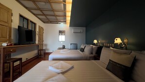A hotel room with two beds, a desk with a television, a window, and a wall-mounted air conditioner. - Cha Na Stay at Merry V (Bangkok)