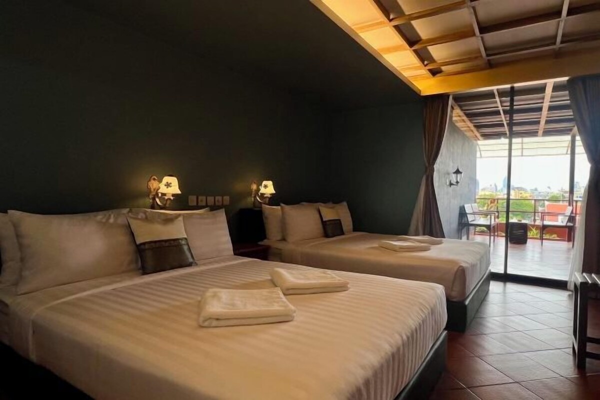 A hotel room with two beds, a balcony with a view, and a ceiling with wooden beams.