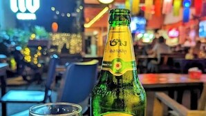 A bottle of Chang Classic Beer and a glass on a table in a bar setting. - Cha Na Stay at Merry V (Bangkok)