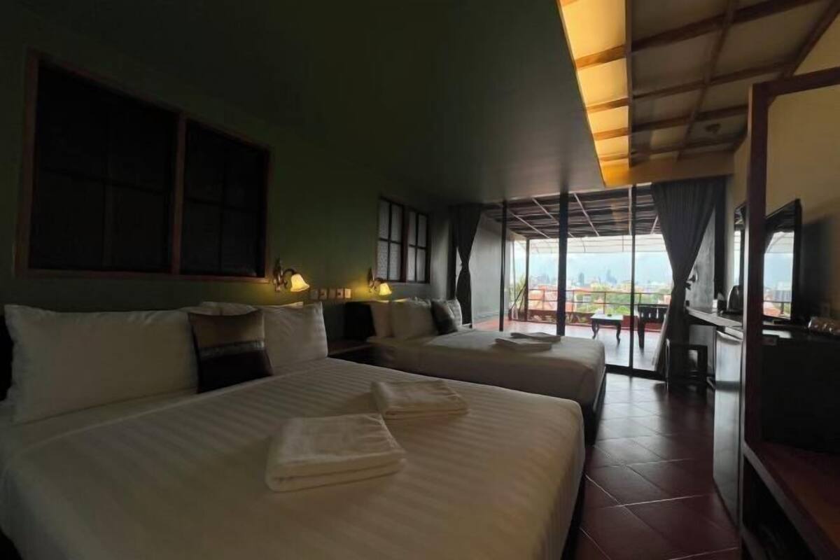 A hotel room with two beds, a balcony, and a TV.