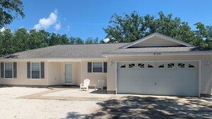 A single-story house with a garage, two windows, and a covered porch with two Adirondack chairs. - Newly Renovated, 1/2 acre home 3 miles from beach (Navarre)