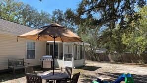 A backyard with a covered patio table, a grill, and a play area with a slide. - Newly Renovated, 1/2 acre home 3 miles from beach (Navarre)