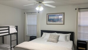A bedroom with a bunk bed, a single bed, a ceiling fan, and a painting of a Venetian lagoon. - Newly Renovated, 1/2 acre home 3 miles from beach (Navarre)
