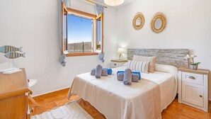 Quarto com uma cama grande, mesa de cabeceira, cortinas e espelhos decorativos na parede.