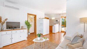 Uma sala de estar moderna com televisão, sofá e uma pequena mesa com uma planta.