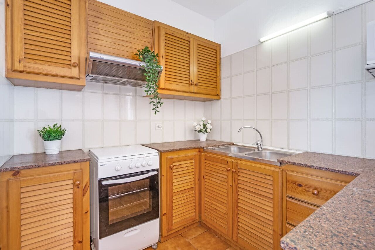 A kitchen with wooden cabinets, a white stove, and a sink.