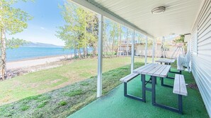 Un espacio al aire libre techado con mesas de picnic y vistas a la playa y las montañas.