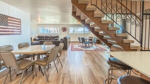 Amplia sala de estar con escalera de madera, una mesa de comedor con sillas y un sofá de cuero.