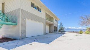A two-story building with a garage door, a small balcony, and a clear view of the mountains in the background. - Bear Lake Paradise | Beach + Boat Ramp (Laketown)