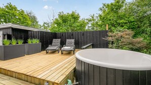 Een houten terras met twee loungestoelen en een whirlpool.