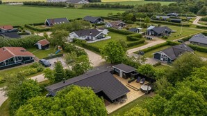 Een woonwijk met huizen, een speeltuin en windturbines op de achtergrond.
