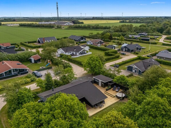 A residential area with houses, a playground, and wind turbines in the background.