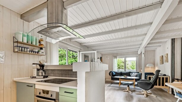 Een moderne keuken met een centraal eiland, inbouwapparatuur en een zithoek met een bank en tafel.