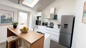 Een moderne keuken met dakraam, een koelkast, en een eethoek met een houten tafel en stoelen.