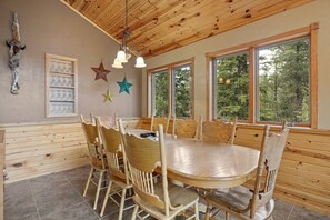 A wooden dining area with a round table and chairs, large windows, and star decorations on the wall. - Flatiron Lodge, Hottub, Secluded (Lead)