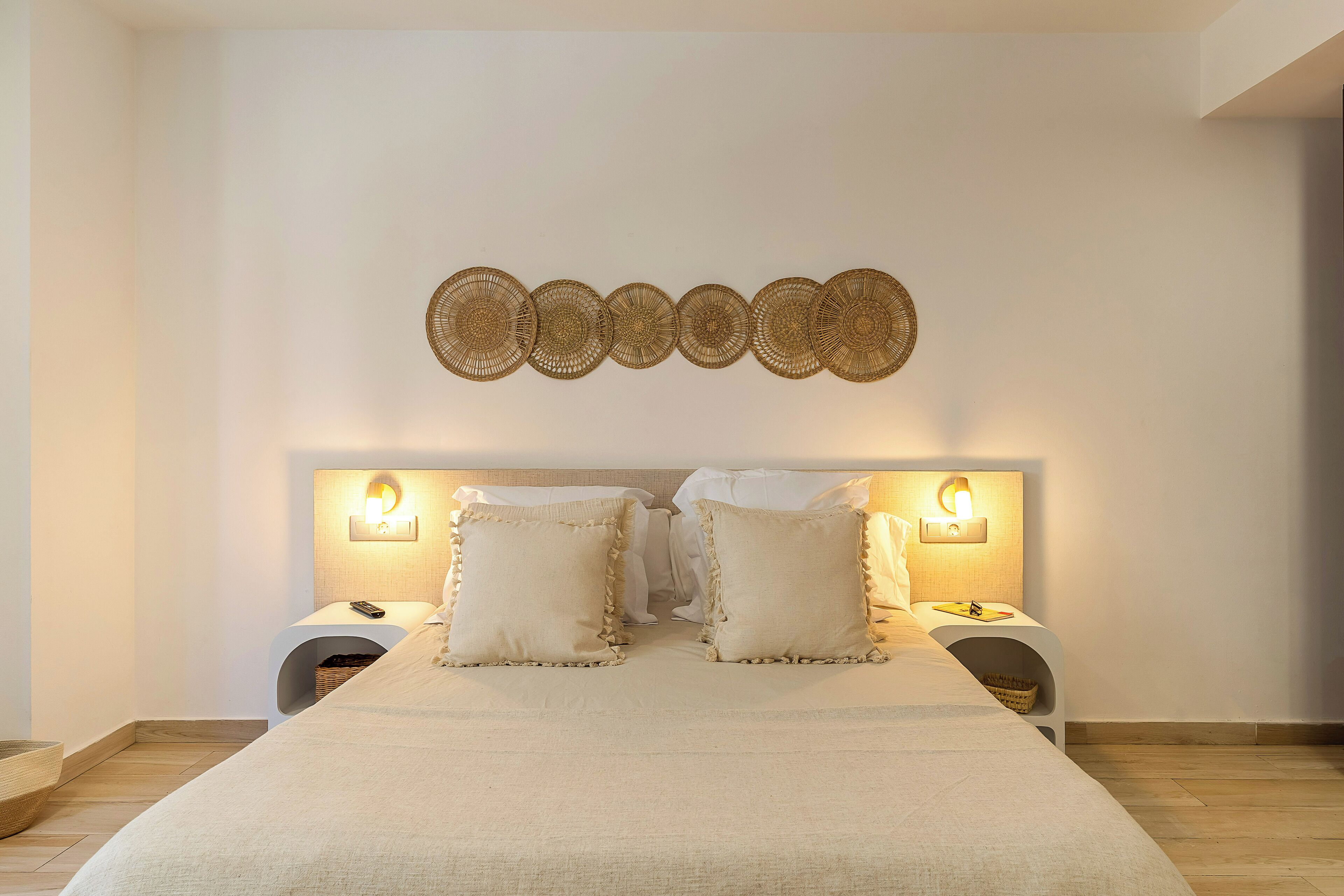 Un dormitorio con una cama grande, dos mesitas de noche con lámparas y un tapiz decorativo sobre la cama.