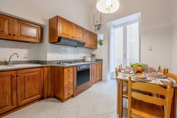 A kitchen with wooden cabinets, a stove, and a dining area with a table set for four.