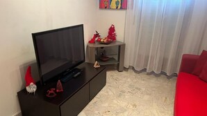 A living room with a black entertainment unit, a red sofa, and a small table with decorative items. - Accogliente Appartamento per Famiglie al Centro (Lavello)