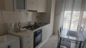 A compact kitchen with a gas stove, oven, and a dining table with chairs. - Accogliente Appartamento per Famiglie al Centro (Lavello)