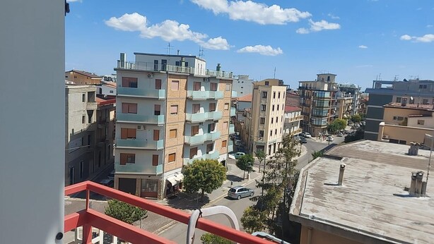 A multi-story residential building with balconies, a clear sky, and a street in the foreground. - Accogliente Appartamento per Famiglie al Centro (Lavello)